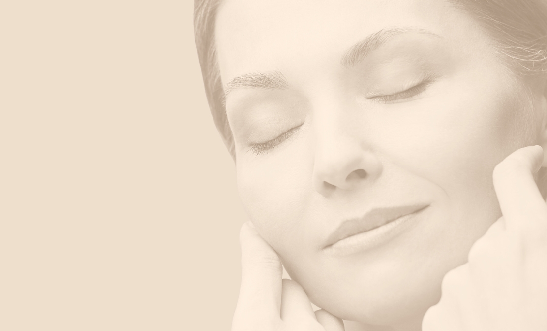 Woman with smooth, rejuvenated skin gently touching face. She is an example of patient goals after Helix Laser Treatment with CO₂ and non-ablative resurfacing treatment at Bellissimo Plastic Surgery.